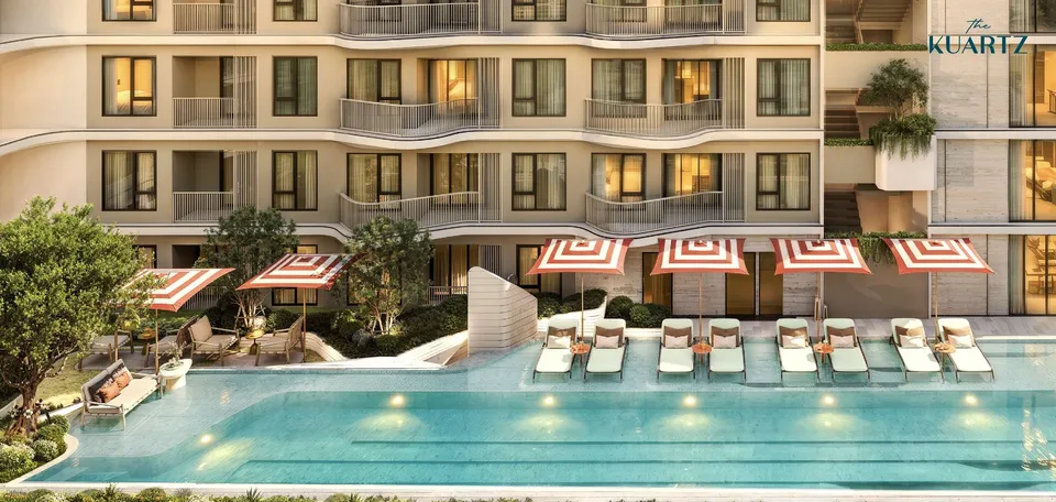 The Title KUARTZ courtyard pool with striped parasols and sun loungers in front of the curved balconies
