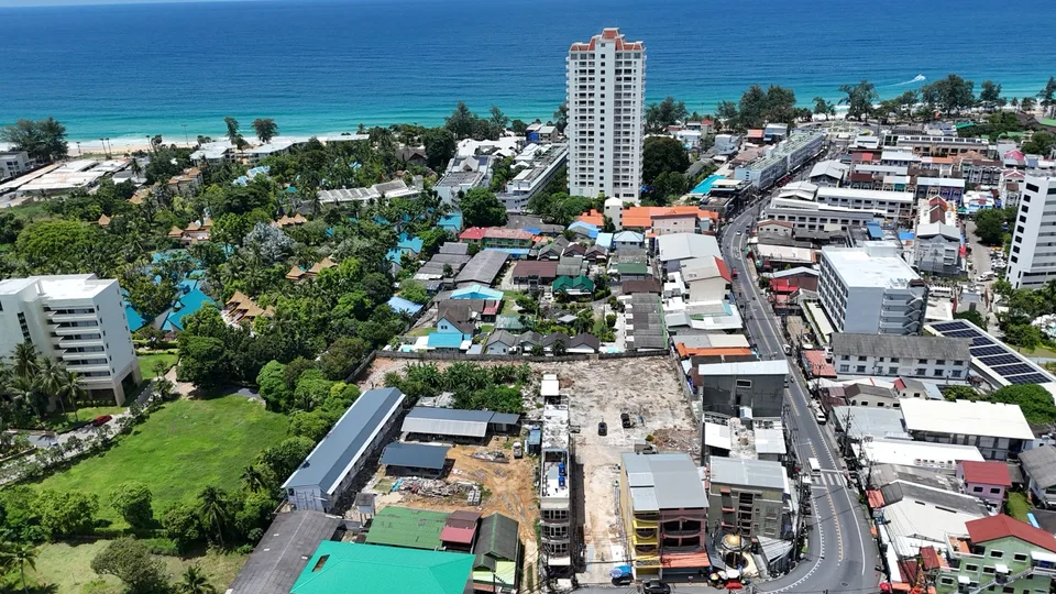 Aerial view of the cleared KUARTZ plot in Karon beside the main road, with Karon Beach and the sea behind