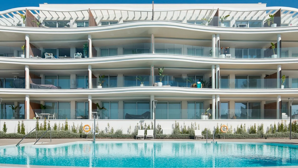 Panoramica by Kronos Homes in Fuengirola: wave-shaped facade above the communal pool