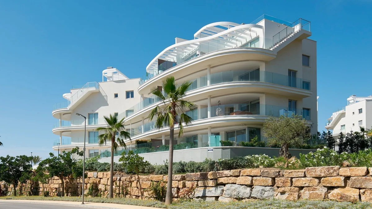 Panoramica, Fuengirola: curved white terraces of the Kronos Homes building above a stone wall