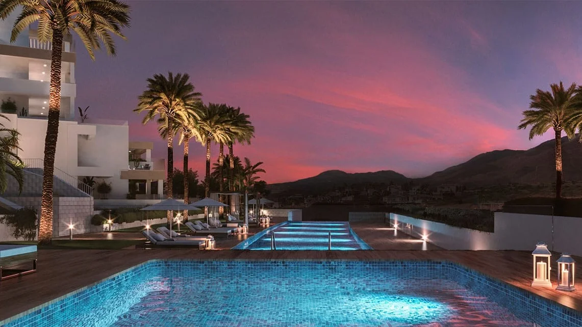 South Bay Las Mesas III communal pool at dusk with palms and mountain view, Estepona